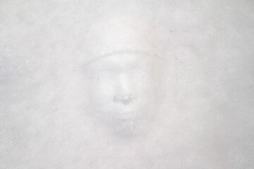 The imprint of a man's face in the snow. Winter.