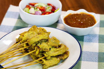 Pork satay in white dish and sauce put on tablecloth
