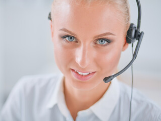 Portrait of pretty young female operator sitting at office desk with headset
