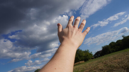 Hand greift nach dem blauen Himmel