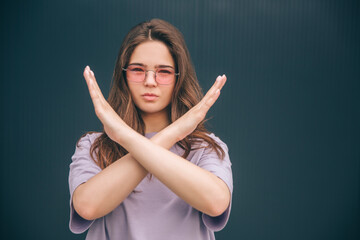 Fototapeta premium Young stylish trendy woman isolated over grey blue background. Girl holding hands crossed in front her. Forbidden sign. Serious concentrated woman on picture.