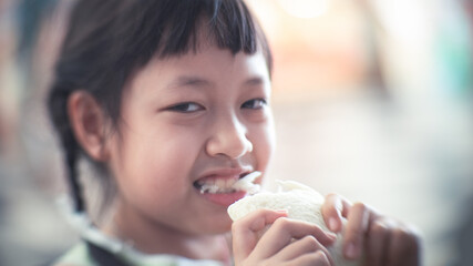 Asian child girl eating some bread with smile and happy