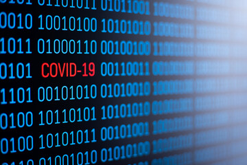 Blue binary code on computer screen with inscription COVID-19 written in red in the middle of the code. Symbol of coronavirus outbreak