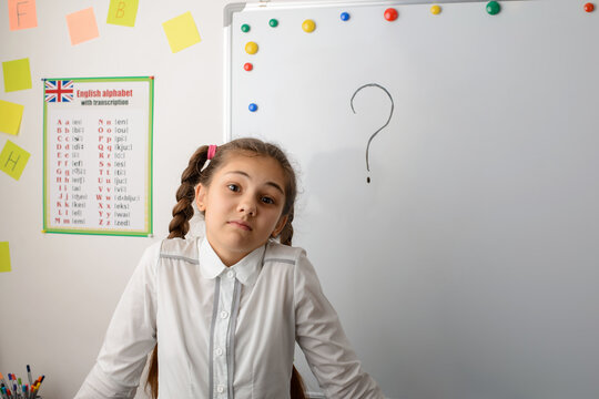Concept of lack of knowledge, misunderstanding, falling far behind classmates. Astonished school girl in school uniform shrugs, doesn't know the answer to the question - Powered by Adobe