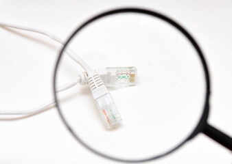 Magnifying glass and twisted pair cable for the Internet on a white background. Gigabit cable view, internet cable through a magnifying glass