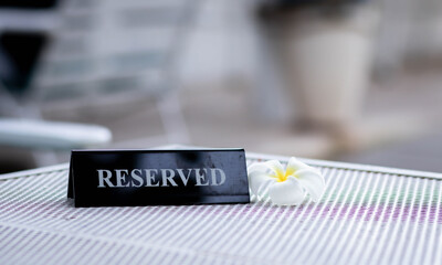 Reserved metal black plate in a restaurant. Reserved metal plate On the white table. vintage photo processing. close up of a setting a reserved sign on the restaurant table.