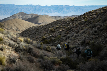 Four male hikers descend into Deadhorse Canyon, part of the popular Cottonwood Canyon- Marble Canyon backpacking loop trail in Death Valley National Park in California