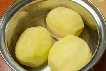 peeled fresh potatoes in a shiny chrome pan