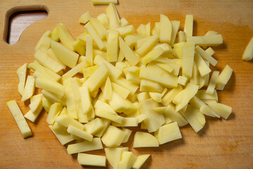 sliced fresh raw potatoes lying on a kitchen wooden board
