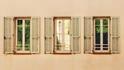 A row of three windows on an old building reflecting the street