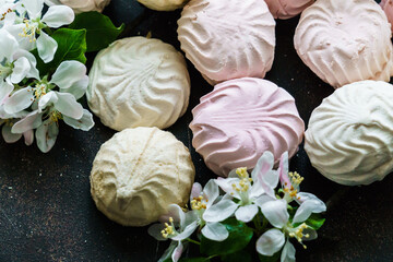Delicious delicate white-pink marshmallows along with a flowering branch of an apple tree.