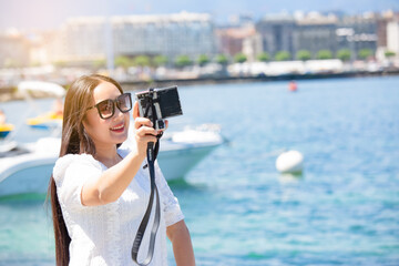 Asian beautiful woman is travel for holiday in the summer of Europe and taking a camera view landscape of lake and bright sky in Geneva Switzerland, copy space.