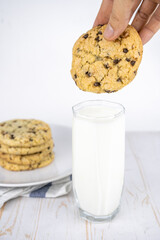 fresh baked classic chocolate chip cookies with nuts on a plate and glass of milk