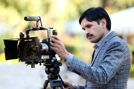 Professional Indian journalist and cameraman recording video or interview. Cameraman in stylish suit recording videos with professional camera and equipment.Shooting a commercial movie.  
