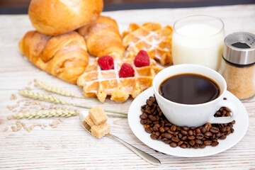 Breakfast in the morning with black coffee cup with bread with Croissant and fruit on the wooden table.