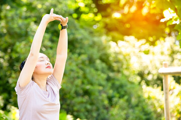 young Asian woman doing yoga fitness exercises in the nature park, Exercise for health or warm-up body, fresh air, or Oxygen in the green tree in the park in sunlight.