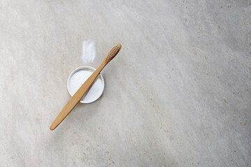 Bamboo toothbrushe and powder for brushing your teeth in bowl on light gray backdrop. No plastic, zero waste concept.