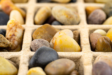 Macro shoot of cardboard extruder filled with colorful decorative pebbles, conceptual photo, space for text, isolated on a white background.