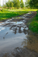 The harsh landscape nature and road through the fields for the off-road SUV with puddles and mud. Autumn or spring background. Forest in the background. Rain-washed road, is impassable, slush, mud