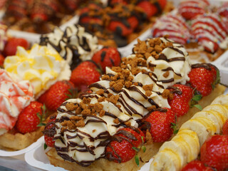 The most delicious Belgian waffles image. Tasty warm waffles with sweet strawberry and other creams. Eating them on the city street is touristic lifestyle of big city. High resolution image in daytime