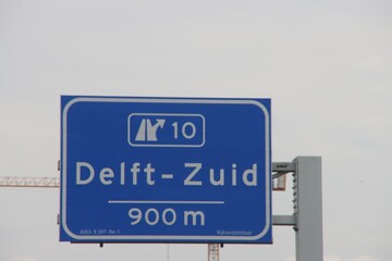 Direction sign in blue and white heading Delft Zuid on motorway A13.