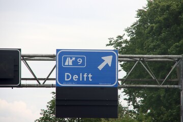 Direction sign in blue and white heading Delft on motorway A13.