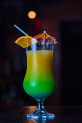 Orange juice in a glass on a bar counter against a dark background.