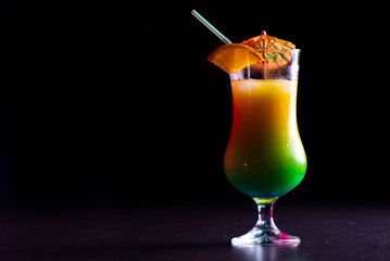 Orange juice in a glass on a bar counter against a dark background.