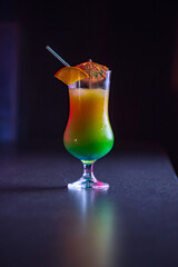 Orange juice in a glass on a bar counter against a dark background.