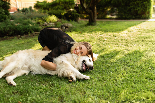 Woman playing with dog Labrador outdoors. Friendship of people and animal