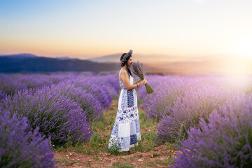 Young woman enjoying the view and the sunlight on her face on a rural flower field with lavender...