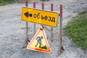 Works ahead warning sign on a road. Road sign road repairs and the sign of the Detour translated from the Russian language