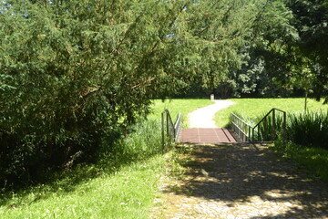 Footpath in a city park with a bridge over a stream