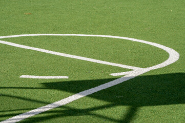 Obraz premium Basket ball court, green grassy ground, artificial grass and white lines. Used by young people in their spare time, to participate in sports activities.