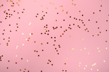 Rose color pastel festive background with golden stars glitter confetti. Flat lay style with copy space for text, design. Trendy Holiday concept. Perfect pink backdrop for social media, blog, postcard