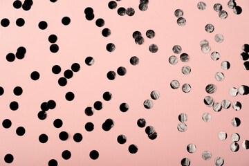 Rose color pastel festive background with holographic black confetti. Flat lay style with copy space for text, design. Trendy Holiday concept. Perfect pink backdrop for social media, blog, postcard.