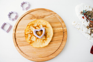 Tasty american pancake with cooking utensils on bright wooden table.