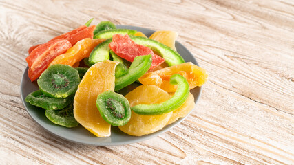 plate of dried fruits on a wooden table. kiwi, mango, papaya, melon, pineapple. do not affects blood sugar levels