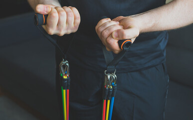 Man doing exercises with resistance bands at home. - obrazy, fototapety, plakaty