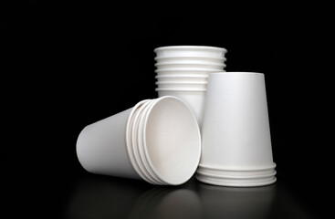 Three stacks of disposable white blank paper cups at black background, restaurant, cafe, drink delivery concept