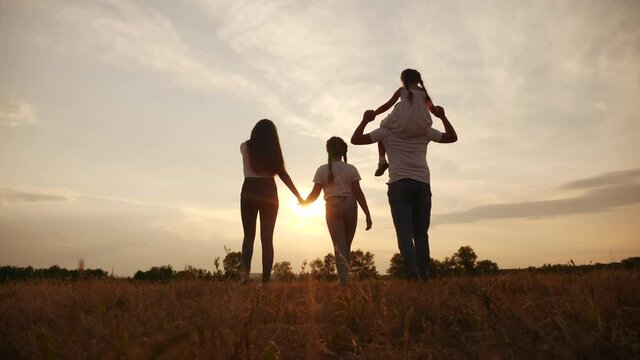 happy family children kids together walk in the park at sunset silhouette. people in the park concept lifestyle mom dad daughter and sister joyful walk. parents and little baby child fun summer