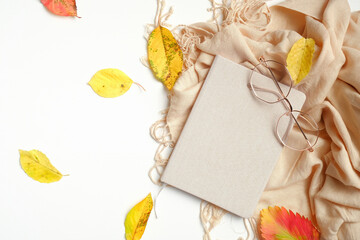 Autumn creative composition. Fallen leaves, paper notebook, women fashion glasses and beige scarf on white background. Autumn, fall concept. Flat lay, top view, overhead.