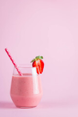 Glass of fresh strawberry milkshake, smoothie and fresh strawberries on pink, white and wooden background. Healthy food and drink concept.
