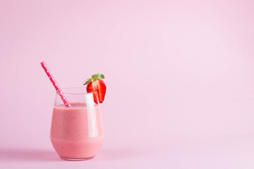 Glass of fresh strawberry milkshake, smoothie and fresh strawberries on pink, white and wooden...