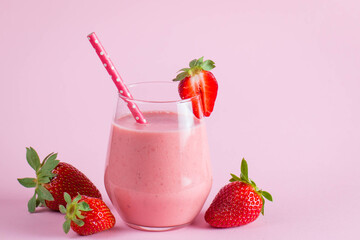 Glass of fresh strawberry milkshake, smoothie and fresh strawberries on pink, white and wooden background. Healthy food and drink concept.
