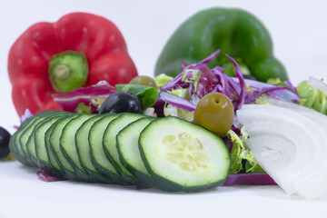 cucumber slices with olives, onion slices and vegetables with two out of focus bell peppers