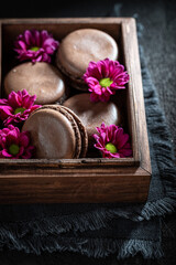 Obraz na płótnie Canvas Closeup of chocolate macaroons in wooden box with flowers