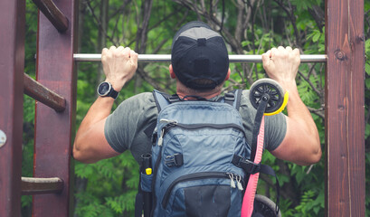 Fototapeta premium Young man pulls himself up - Exercises in the fresh air - Milenials practicing sleep on a ladder - Holiday trip and exercises in the park