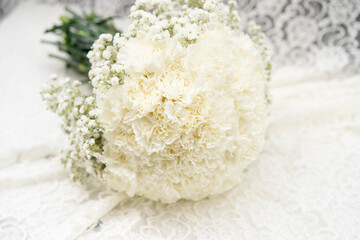 Round white bridal bouquet on table with lace fabric and wedding decorations
