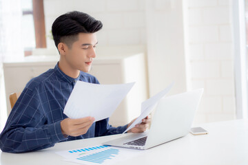 Young asian business man looking document data graph and chart paper, marketing and investment, report of statistics profit for financial, economic and growth of finance, management and planning.